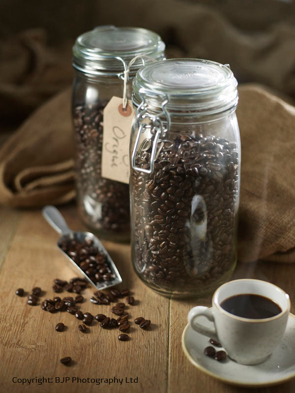 #HEXLife coffee beans in a jar and a cup of coffee on a wooden bench with hessian background.